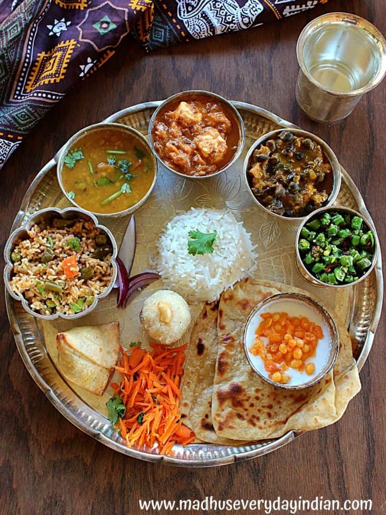 silver thali with rice, curries and rava ladoo