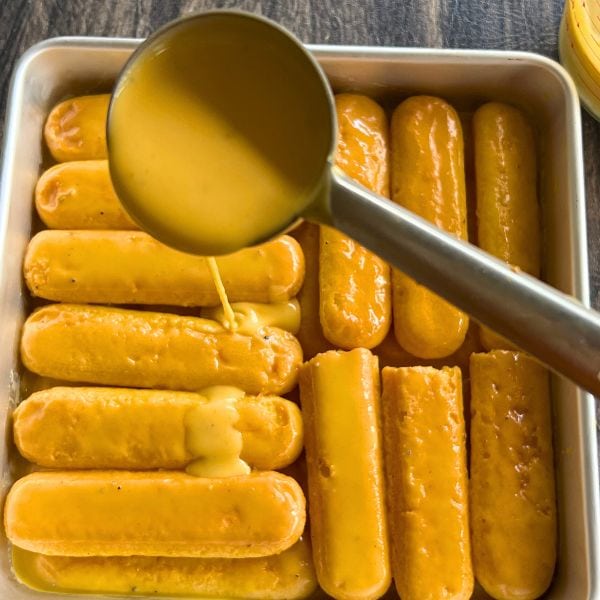 mango milk mixture poured on the lady fingers