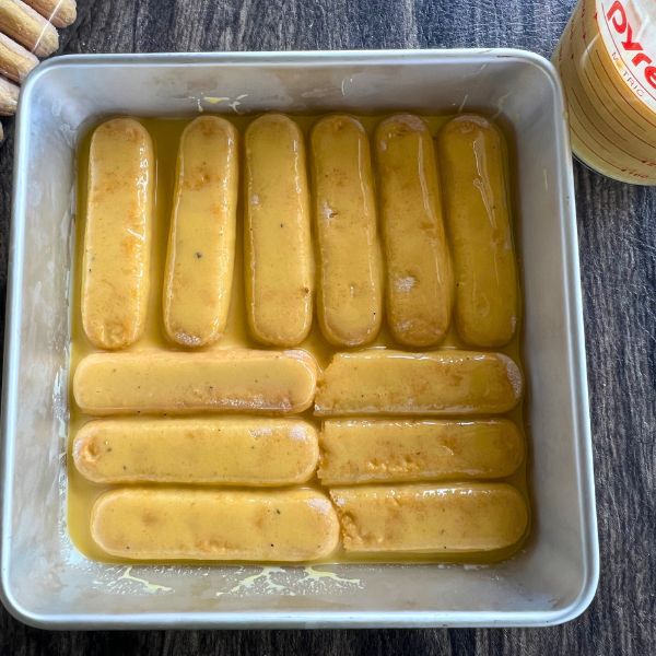 lady fingers soaked in milk milk mixture and layered in a pan